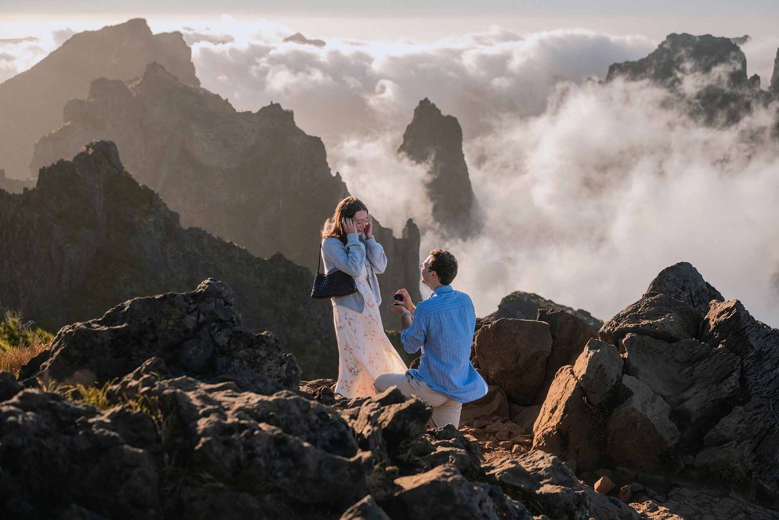 A guy proposes above the clouds at sunset time, at Juncal viewpoint, Madeira Island